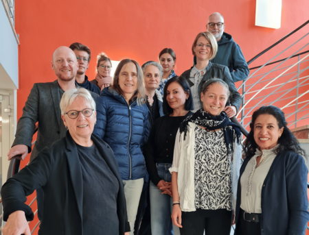 Ein Gruppenbild auf einer Treppe vor einer roten Wand