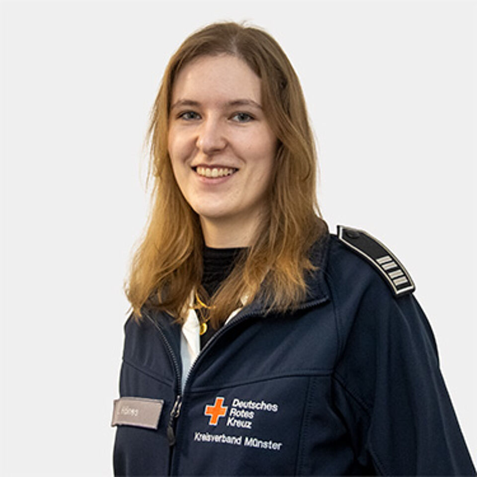 Eine Frau mit braunen langen Haaren in einer blauen Rotkreuz-Jacke