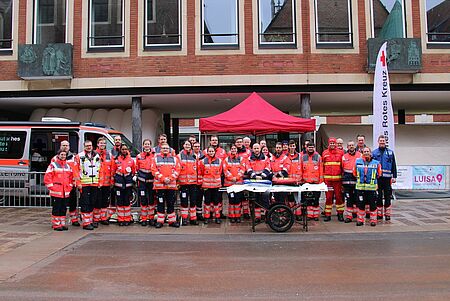 Gruppenbild von 100 Ehrenamtlichen in Einsatzkleidung. Im Hintergrund sind Zelte und Pavillions zu sehen.