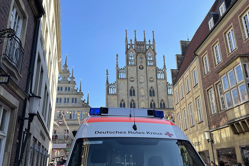 Das Dach eines Krankentransportwagens des DRK ist vor historischen Gebäuden zu sehen.