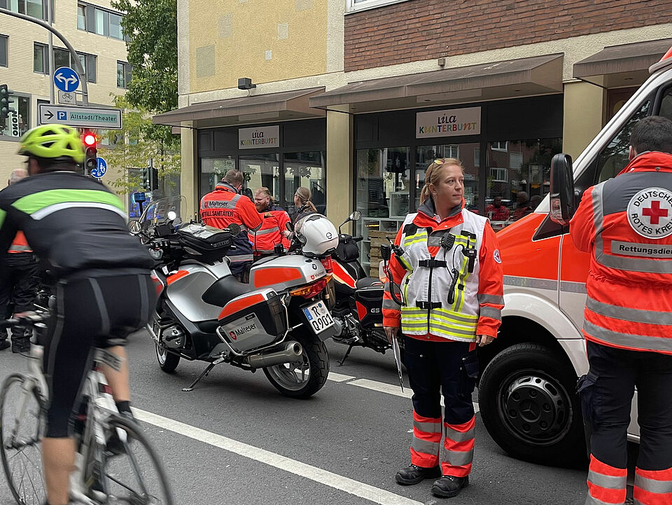 Giro 2025 Rettungskräfte stehen neben Motorrädern und einem Rettungsmittel am Straßenrand, ein Radfahrer fährt vorbei.